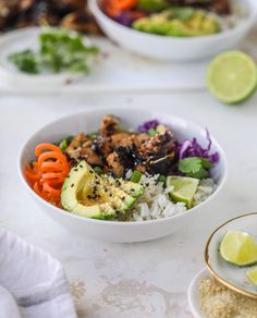 a white bowl filled with rice, meat and veggies on top of a table