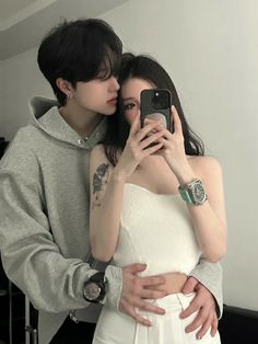 a man and woman taking a selfie in front of a mirror with their arms around each other