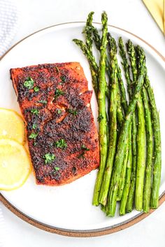 grilled salmon and asparagus on a plate with lemon wedges next to it