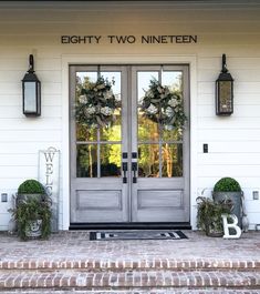 two wreaths are placed on the front steps of a white building with doors that say eighty two nineteen