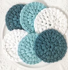 four crocheted coasters sitting on top of a white plate