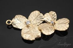 three gold flower charms with diamonds on them