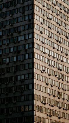 a very tall building with lots of windows on it's side and an airplane flying in the air