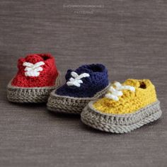 three crocheted baby shoes sitting on top of a gray floor next to each other