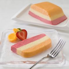 two slices of cake on a plate with a fork next to it and another piece of fruit in the background