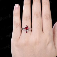 a woman's hand with a ring on it and a red stone in the middle