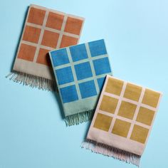 two scarves on a blue background, one is orange and the other is pink