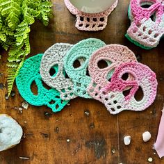 several crocheted objects on a wooden table next to a cup and pot holder