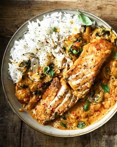 a white plate topped with meat and rice on top of a wooden table next to a fork