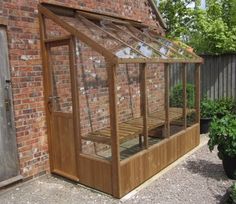 a small wooden greenhouse in front of a brick building