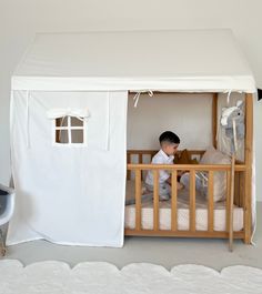 a little boy that is sitting in a bed with a tent on top of it