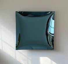 a square shaped mirror hanging on the wall