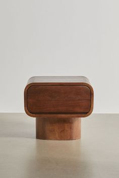 a small wooden box sitting on top of a table next to a white wall and floor