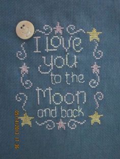 a close up of a cross stitch on a piece of cloth with the words i love you to the moon and back