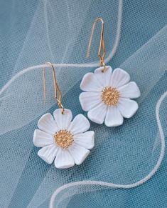 two white flowers are hanging from gold ear wires