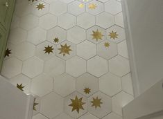 some gold stars on a white tile floor in a room with green doors and cabinets