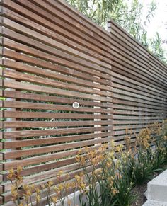 a wooden fence with flowers growing along it