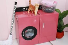 a pink washer and dryer sitting on top of each other next to a potted plant