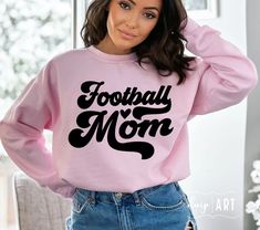 a woman wearing a pink football mom sweatshirt with the words football mom printed on it