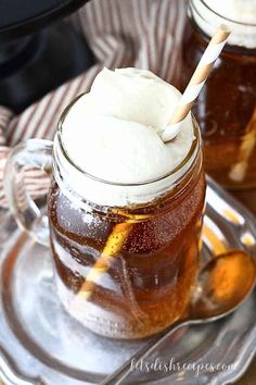 two mason jars filled with ice cream on top of a glass plate next to spoons