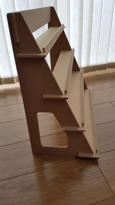 a book shelf sitting on top of a hard wood floor next to a white curtain