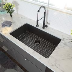 a kitchen sink sitting under a window next to a counter top with flowers on it