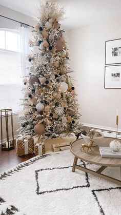 a living room decorated for christmas with a white and gold tree in the corner next to a window