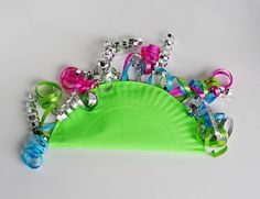 a green paper plate topped with lots of bracelets and bows on it's side