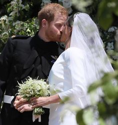 a bride and groom kissing in front of a tree