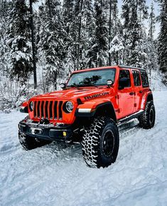 a red jeep is driving through the snow