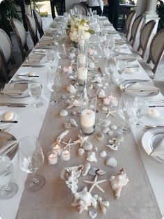 a long table is set with candles and seashells