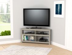 a flat screen tv sitting on top of a wooden entertainment center next to a window