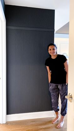 a woman standing in front of a black wall with vertical blinds on it's side