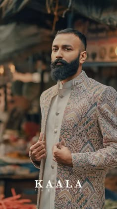 a man with a beard wearing a jacket and standing in front of an open market