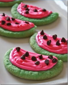 cookies decorated with pink and green frosting on a white platter, ready to be eaten