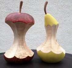 two wooden vases sitting side by side on a table with one apple and the other pear