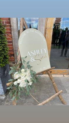 a wedding sign with flowers on it sitting in front of a wooden easel that says ashley and still