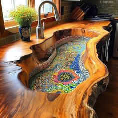 a sink made out of wood with colorful designs on the counter top and below it is a potted plant