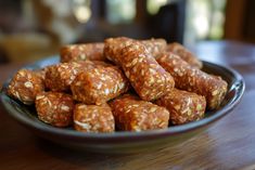 a plate full of granola bites sitting on a wooden table with a blurry background