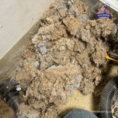 a pile of dirt sitting next to a pair of shoes on top of a floor