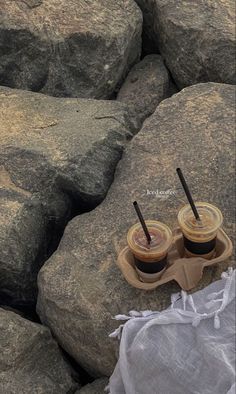 two cups of coffee sitting on top of some rocks