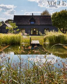 a house sitting on top of a lush green field next to a lake filled with water