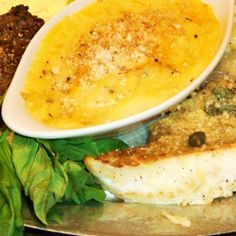 a plate with some food on top of it and greens in front of the plate