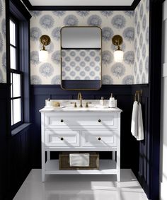 a bathroom with blue and white wallpaper, two sinks and a gold framed mirror