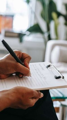 a person writing on a notepad with a pen in their hand and a clipboard next to them