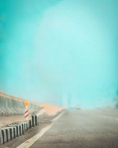 a blurry photo of an empty street with traffic cones on the side and blue sky in the background