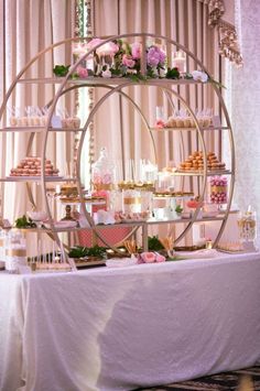 a table topped with cakes and desserts under a circular display shelf filled with cupcakes