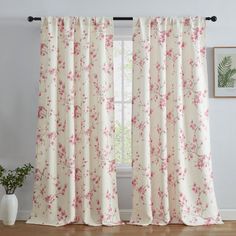 the curtains in this room are pink and white with red flowers on them, along with a potted plant