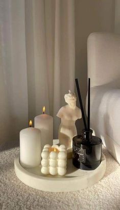 white candles are sitting on a tray in front of a bed