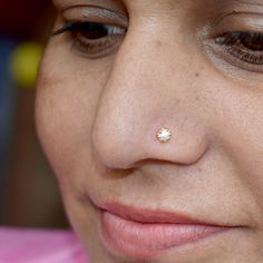 a close up of a woman with a nose piercing on her nose and wearing a pink shirt